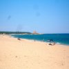 Spiaggia sabbiosa con ombrelloni e mare azzurro.