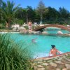 Piscina con ponte in legno e vegetazione tropicale.