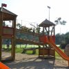 Struttura per bambini con ponti e scivoli gialli su prato.