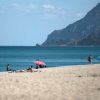 Spiaggia sabbiosa con ombrelloni colorati.