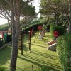 Parco giochi con altalene e alberi, bambini che giocano.