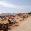 Spiaggia con ombrelloni arancioni e sdraio, vista mare.