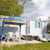 Casa mobile bianca con gazebo e sedie.