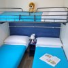 Letto a castello e due letti singoli con coperte blu.