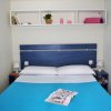 Letto matrimoniale con coperta azzurra, mensola bianca sopra.