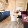 Cucina con tavolo, sedie bianche e divano marrone.