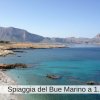 Spiaggia con acqua blu e montagne sullo sfondo.