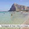 Spiaggia con mare cristallino e montagna sullo sfondo.