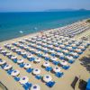 Una spiaggia con ombrelloni bianchi e lettini blu allineati, vista sul mare.