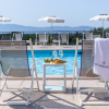 Due sedie a sdraio con tavolino, cibo, bevande e una piscina sullo sfondo.