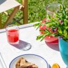 Bevanda rossa e crostata su tavolo bianco con pianta fiorita.