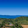 Vista panoramica di un paesaggio costiero con colline verdi e mare azzurro.