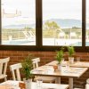 Sala da pranzo con finestre vista piscina, sedie bianche e piante sui tavoli.