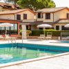 Una piscina con lettini e ombrelloni, affiancata da villette con tetti rossi.
