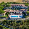 Complesso residenziale con piscina e verde circostante, situato tra le colline.