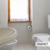 Bagno con lavandino, WC e finestra, interni bianchi.