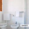 Bagno con WC, bidet, doccia e finestra, interni bianchi.