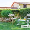 Due sedie e un tavolino con caraffa e bicchieri in un giardino.