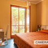 Camera da letto con letto matrimoniale e scrivania, porta finestra aperta.