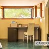 Scrivania con sedia, finestra aperta e piante su pavimento piastrellato verde.