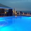 Piscina illuminata di sera con una tenda e sedie a sdraio al bordo.