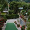 Un ingresso con passerella verde, piante fiorite ai lati e bandiere in lontananza.