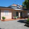 Esterno di una casa rosa con veranda e giardino.