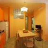 Cucina moderna con mobili arancioni e tavolo da pranzo al centro.