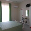 Camera con letto verde e tendaggi coordinati. TV e armadio in un angolo.