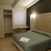 Camera con letto verde e parete nera. Guarda robe aperto e finestra con tendina chiusa.