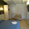 Camera con letto blu e un divano beige. TV a parete e guardaroba aperto.