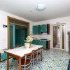 Cucina moderna con mobili verdi, tavolo con sedie e pavimento con piastrelle colorate.