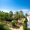 Vista di giardini con palme e edifici bianchi sotto un cielo azzurro.