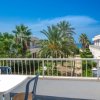 Tavolo con sedie su un balcone che affaccia su giardini e mare.