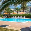 Piscina all'aperto circondata da lettini bianchi e ombrelloni arancioni.