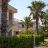 Palazzine bianche con palme intorno e vialetto piastrellato.