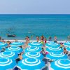 Spiaggia affollata con ombrelloni azzurri e mare blu sullo sfondo.