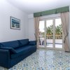 Soggiorno con divano blu, pavimento decorato, porta finestra con tende e vista su palme.