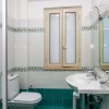Bagno con piastrelle verdi e bianche, lavandino, specchio, toilette e finestra.