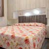 Camera da letto con letto matrimoniale e copriletto colorato, armadi sopra il letto.