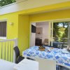 Terrazza gialla con tavolo apparecchiato e sedie, vista su un giardino verde.
