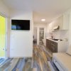 Soggiorno con cucina, pavimento in legno multicolore, TV a parete e divano beige.