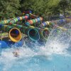 Scivoli d'acqua colorati con gente che si tuffa in piscina, creando grandi schizzi.