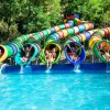 Cinque persone che escono da scivoli d'acqua colorati, atterrando in piscina.