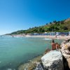 Spiaggia con mare calmo e colline in lontananza.