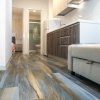 Un appartamento con pavimento effetto legno, cucina moderna e divano beige.