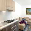 Cucina moderna con lavello, fornelli, un divano beige e un dipinto colorato su parete.