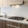 Cucina con lavello acciaio, fornelli a gas, e mobili in legno chiaro.