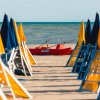 Ombrelloni gialli e blu su spiaggia con barca rossa.