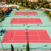 Tre campi da tennis con superfici rosse e recinzioni verdi.
